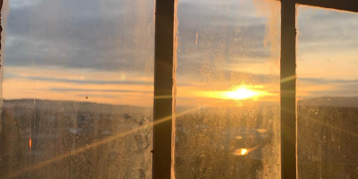 Blick durch ein Fenster auf einen Sonnenuntergang